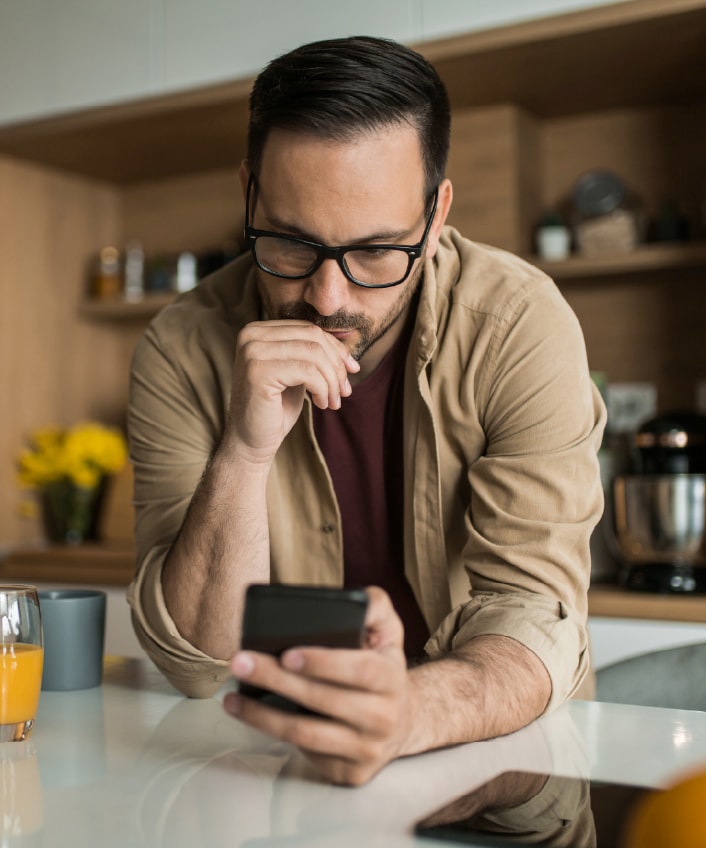 A man looking at his phone learning about clone phishing.