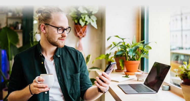 Man holding a mug and a mobile phone.